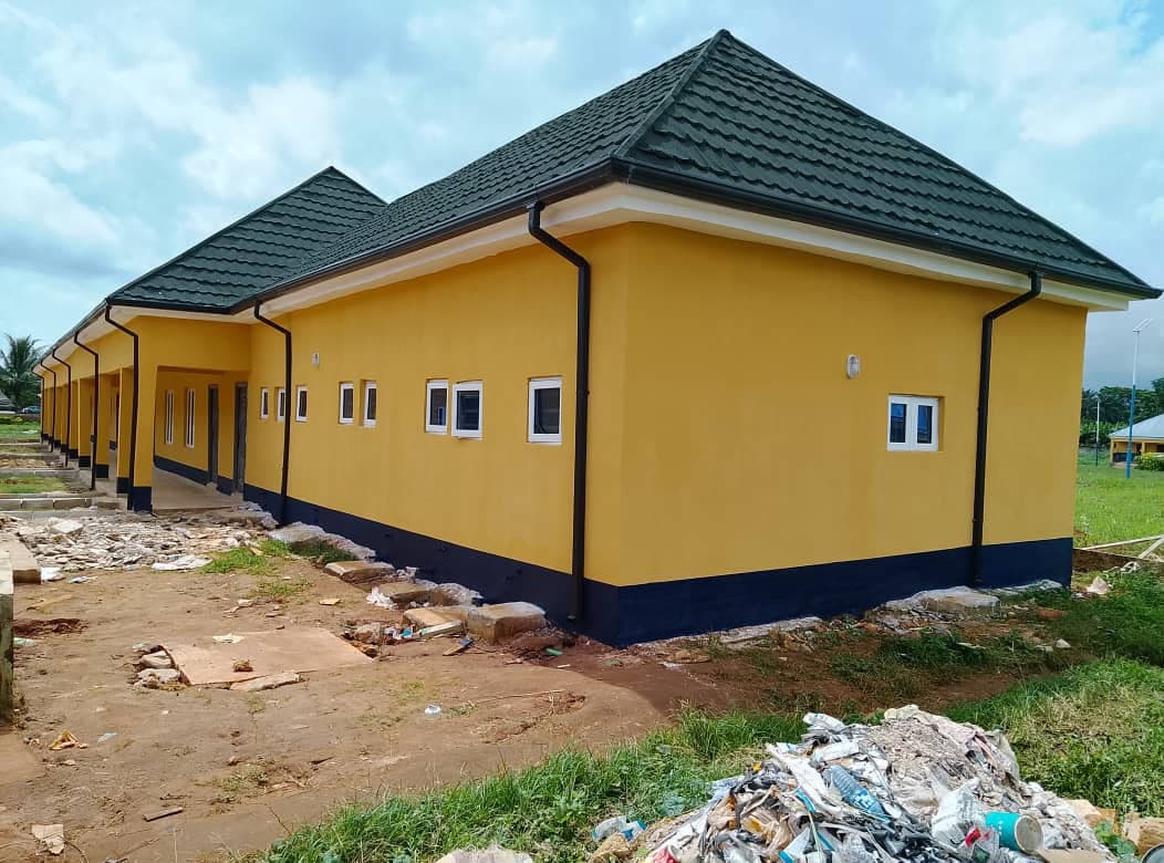 Finished accommodation block. Completed single-storey block with yellow render, navy plinth band and dark pitched roof.
