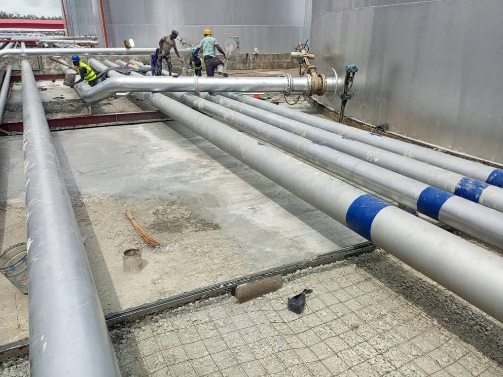 Pipework on a concrete pad. Process pipework laid across a reinforced concrete pad beside a storage tank.