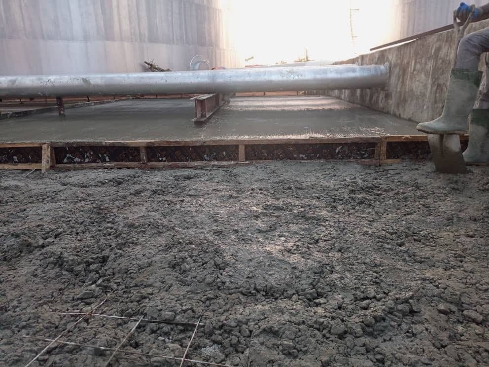 Fresh concrete placed against timber formwork, with pipework above
